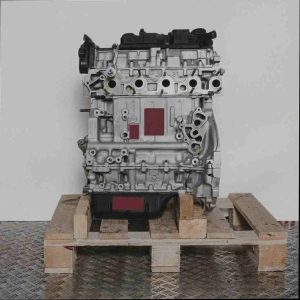 Motor 9HF (DV6DTED) auf Holzpalette vor weißem Hintergrund. Der silberfarbene Motor mit schwarzen Komponenten ist vertikal ausgerichtet.