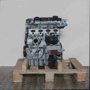 Silberner Motor BLX auf Holzpalette vor weißem Hintergrund. Seitenansicht des kompletten Motors mit detaillierten mechanischen Komponenten.