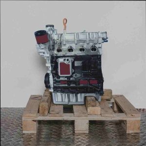 BMY Automotor auf Holzpalette vor weißem Hintergrund. Der silberne Motorblock und die schwarze Ölwanne sind deutlich zu sehen, ebenso wie der orangefarbene Ölmessstab.