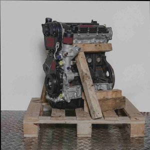Schwarzer und grauer Motor CJSA auf Holzpalette vor weißem Hintergrund. Seitenansicht des Motors ohne Logos oder Overlays.