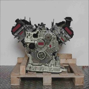 Motor CKVC auf Holzpalette vor weißem Hintergrund. Der V-förmige Motor mit grauen und schwarzen Komponenten ist vollständig sichtbar.