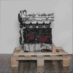 K4M 750 Motor auf Holzpalette vor weißem Hintergrund. Der Motor, vertikal ausgerichtet, zeigt silberne und schwarze Elemente. Ein detailliertes Bild des Motors.