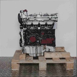 Seitenansicht eines K4M 752 Motors auf einer Holzpalette vor weißem Hintergrund. Der Motorblock ist schwarz, der Zylinderkopf und die Ölwanne silbern.