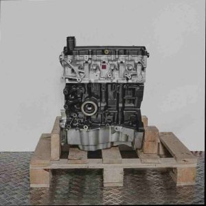 Seitenansicht eines Motors K9K 702 auf einer Holzpalette vor weißem Hintergrund. Der Motor ist vertikal ausgerichtet.