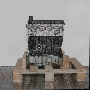 Seitenansicht des Motors K9K 710 auf einer Holzpalette vor weißem Hintergrund. Der Motor ist vollständig sichtbar, inklusive Zylinderkopf, Motorblock und Ölwanne.