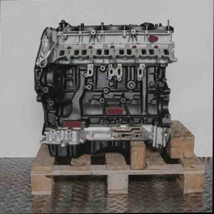 SA2R Automotor auf Holzpalette vor weißem Hintergrund. Schwarzer Motorblock, silberne Teile. Seitenansicht des Motors.