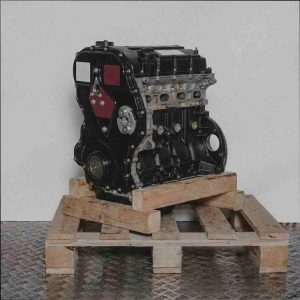 Schwarzer Automotor SA2S auf Holzpalette vor weißem Hintergrund. Seitenansicht des Motors, vertikal ausgerichtet.