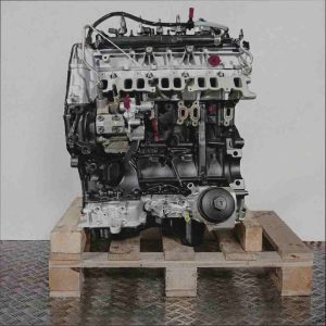 Seitenansicht des Motors T22DD0P in Schwarz und Silber auf einer Holzpalette vor weißem Hintergrund. Gelbe und rote Akzente an Schläuchen und Verschlüssen.